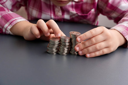 Child's hands with coins on grey background, closeup. Money savings conceptの写真素材