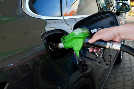 Hand refilling a car with fuel at a gas station, closeup