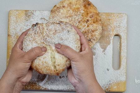 Woman's hands holding a freshly baked buns on a cutting board
