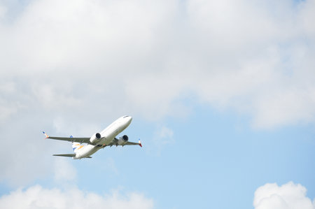 Airplane flying in the blue sky with white clouds on a sunny dayの写真素材