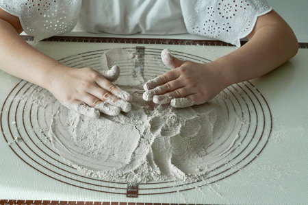 Children's hands knead the dough on a table in the kitchenの写真素材