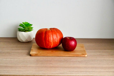 Pumpkin and apple on wooden table with white wall background.の写真素材