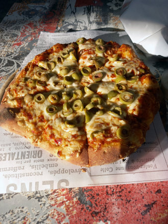 Pizza with green olives on a rustic wooden table.の写真素材