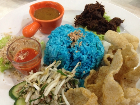 This is a traditional Malay rice dish called Nasi Kerabu usually served with beef rendang  crackers raw vegetables and condiments. The blue coloured  rice comes from the natural colouring of a type of flower found in Malaysia.の素材
