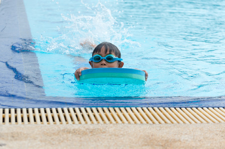 Happy little kid boy having fun in an swimming pool
