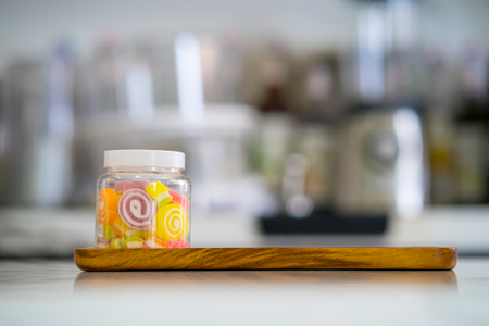 colorful sweet jelly candies in bottle on wooden plate at coffee shopの写真素材