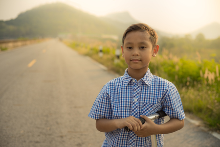 Boy standing catching scooter at Bang Phra Reservoir chonburi thailand. at Sunsetの写真素材