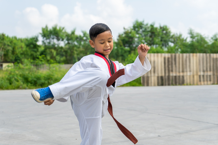 Asian boy wearing white Taekwondo suit acting kick to battle, Sport Conceptの写真素材