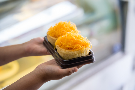 Gold Egg Yolk Thread Cakes on kid hand, Thai sweet foodの写真素材