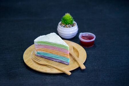 Rainbow crepe cake with strawberry jam on wooden plateの写真素材