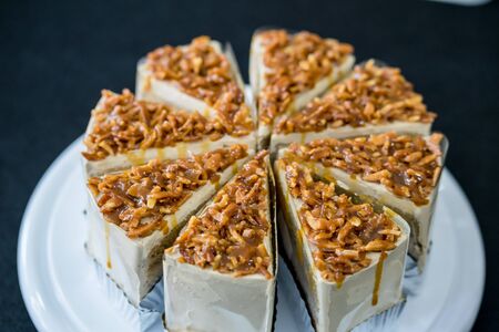 piece of Coffee almond caramel cake on white plate in coffee shop on black backgroundの写真素材