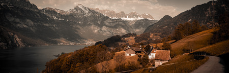 Vintage panorama in Swiss Alps - Vintage panoramic view over the lake Walensee and the surrounding hills and villages, with the Swiss Alps in background and a dramatic gray sky. Picture taken in the village Unterterzen, Switzerland.の写真素材