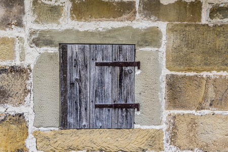 Stone wall with a wooden trapdoor - Medieval architecture background with a stone wall and a small...