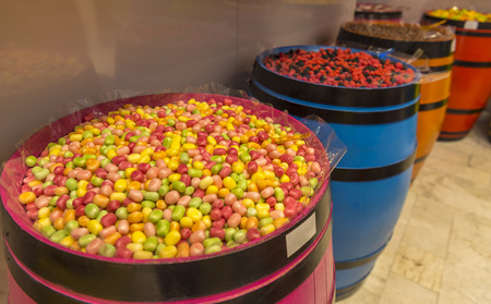 Delicious treats, candies in many colors and shapes, displayed in colorful wooden barrels.
