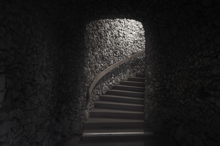 Old dark cellar made from small pieces of stone and staircase towards the exit and light.の写真素材