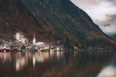 Famous Hallstatt, an Austrian town, on the Hallstatter lakeshore, at the foot of the Dachstein Mountains, surrounded by autumn colored forest.の写真素材