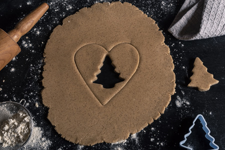 Above view with christmas baking table, gingerbread dough with a heart and tree shape cut from itの写真素材