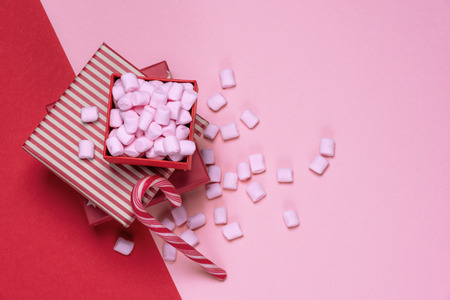 Minimalist Christmas gifts and sweets image with red presents and an open box full of pink tiny...