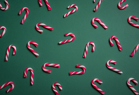 Above view of mini red and white candy canes displayed on a green paper background. Christmas sweets context. Minimal image.の写真素材