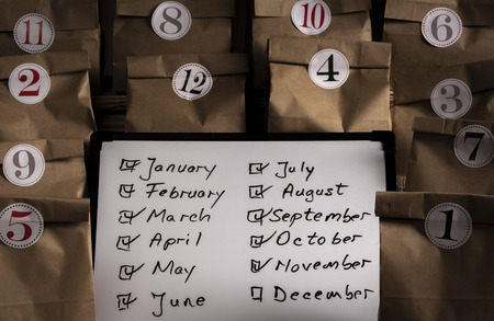 Writing board with the list of the months of the year and paper bags numbered from 1 to 12 with...