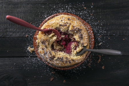 Directly above image of a raspberry pie in a ceramic pan, with two spoons in it, on a rustic table. Devouring a savory pie. Homemade delicious pie.の写真素材
