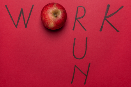 Work word wrote with an apple instead of the letter o and the word run, on a red background. Above view. Work, eat healthy and do sports concept.の写真素材