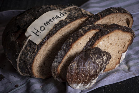 Fresh homemade black bread on a kitchen towel, sliced in pieces. Traditional german bread with rye...