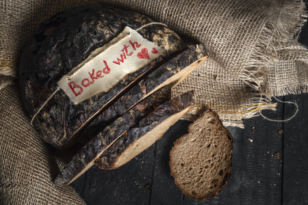 Crusty German brown bread and baked with love message on a tag, on a jute sack. Healthy rye bread....