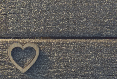 Heart shaped wooden piece on an outdoor frozen bench in the light of sunrise