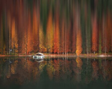Colorful autumn forest with motion blur artistic effect, reflected in the water of the Alpsee lake, near Fussen city, Germany.の写真素材