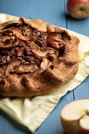 Rustic galette with crispy apple slices and pecan nuts. Autumnal specific apple pie on a wooden tableの写真素材