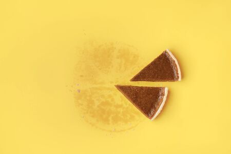 Flat lay of traditional American dessert with two pieces of pumpkin pie and grease traces of the whole pie, on a yellow background. Thanksgiving pie.の写真素材