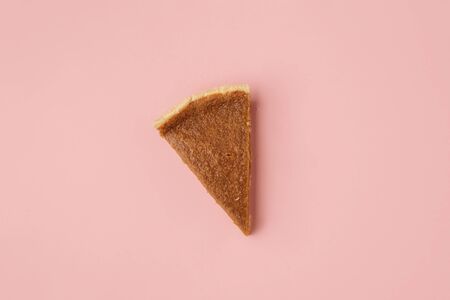 Traditional pumpkin pie slice on pink paper background. Above view of one pie portion. Minimal image of the last pie slice. Thanksgiving dessertの写真素材