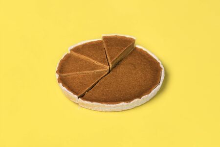 Pumpkin pie slices displayed on uneven heights, on a yellow background. Pie chart concept. Traditional american sweet pastry. Thanksgiving dessert.の写真素材