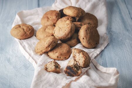 Hot buns freshly baked with rye flour and nuts, on a kitchen towel on a wooden table. Close-up of...