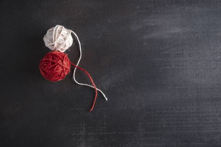 Knitting concept with red and white cotton coils on a black background. Above view of two thread balls.の写真素材