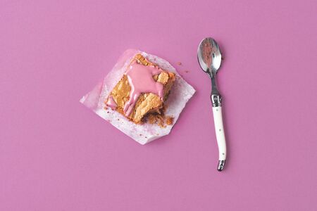 Piece of pink brownie dessert eaten with a spoon on a pink background. Minimal image of eating ruby chocolate cake. Above view of pink dessert.の写真素材