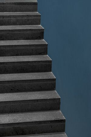 Concrete stairs and blue wall inside a modern building. Home interior staircase and a blank wall