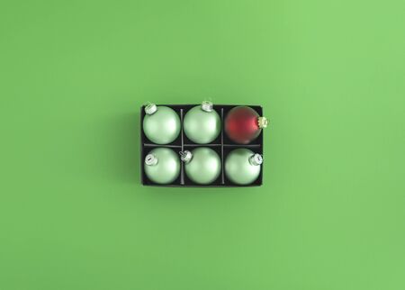 Green Christmas balls and just one red bauble in a black box on a green background. Xmas traditional decorations. Flat lay of Christmas ornaments.の写真素材
