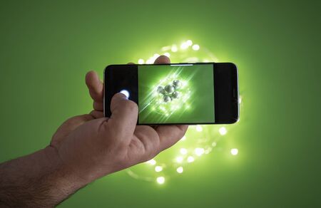 Photographing Christmas lights and Xmas balls with a smartphone, over a green background. Using a...