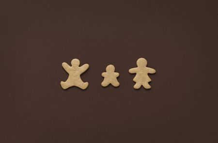 Family for Christmas concept with gingerbread cookies in shape of parents and child, minimal, on a brown background. Above view of Christmas sweets.の写真素材