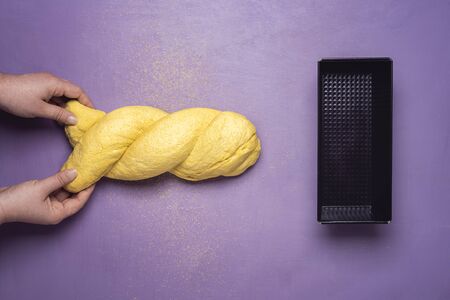 Baking corn bread concept with woman molding yellow dough into corn bread over purple table.の写真素材