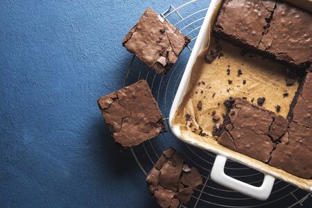 Best brownies dessert in a white pan and on a cooling tray, on phantom blue table. Above view of...