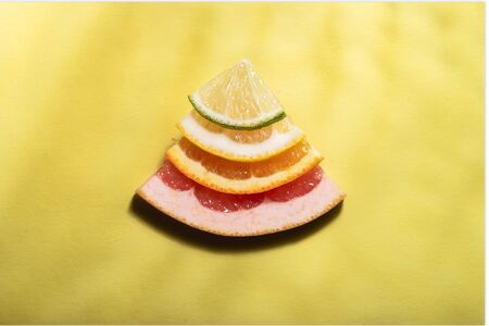 Citrus fruits slices in a stack, in the summer sun, on a yellow background. Sunny day and citrus...
