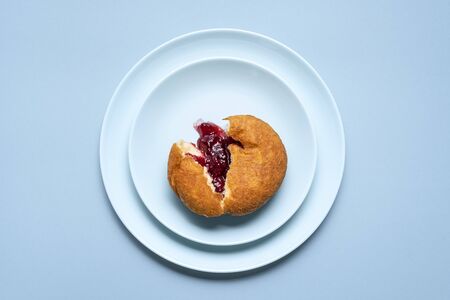Single berliner doughnut sliced, with raspberry jam on blue plates and seamless background. Above view of homemade jelly donut. Famous german doughnutの写真素材