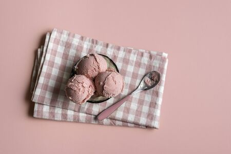 Raspberry ice cream in a glass bowl on napkin, on pink seamless background. Above view of berries...