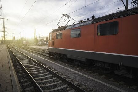 Electric locomotive on railroad tracks in Singern train station, Germany, at sunset. Eco-friendly...