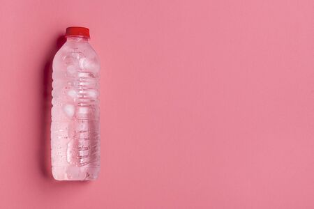 Frosty plastic bottle with clean fresh water. Cold water in a plastic bottle on a pink background...