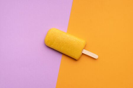 Orange flavored ice cream  on a seamless colorful background. Flat lay of one fruity  . Vegan ice...