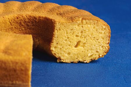 Close-up of a sliced cornmeal cake on a blue background. Sponge cake made with cornmeal. Fest junina...